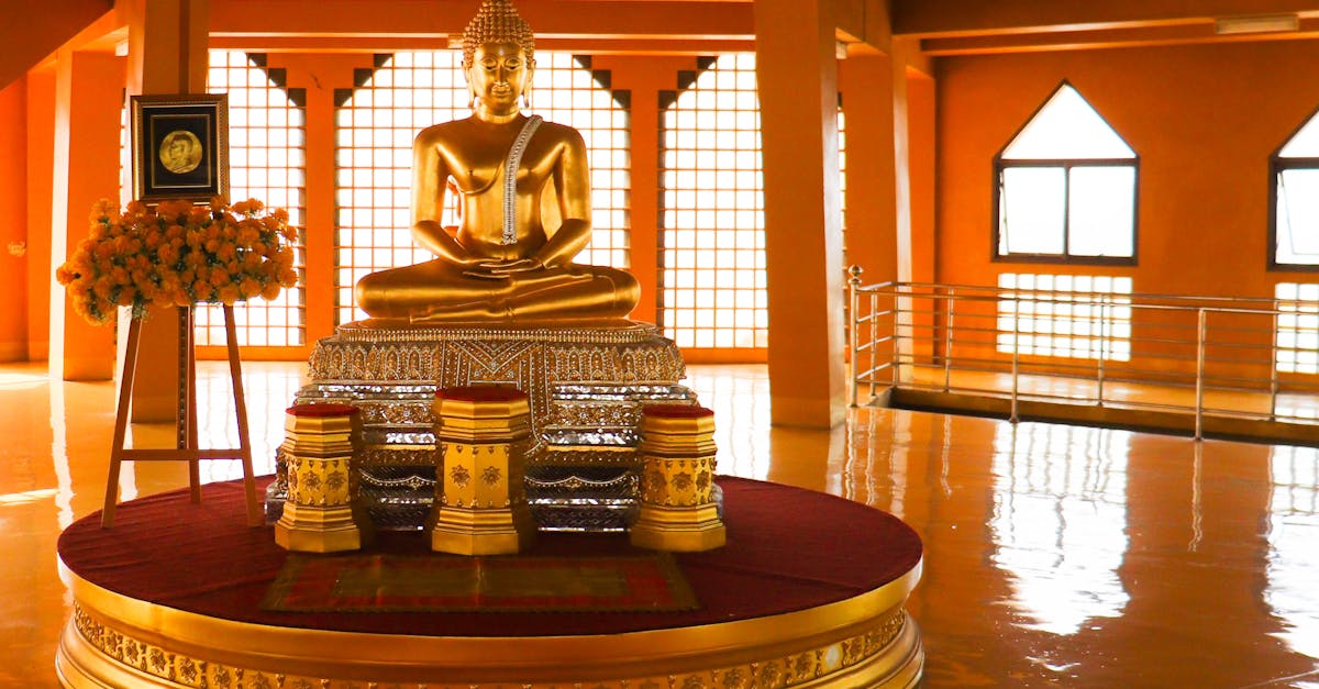 Interior of modern Asian temple with big golden Buddha statue in center in daylight