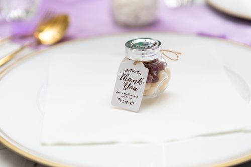 Free Close-up of a small glass jar with a thank you tag placed on a plate, perfect for weddings or events. Stock Photo