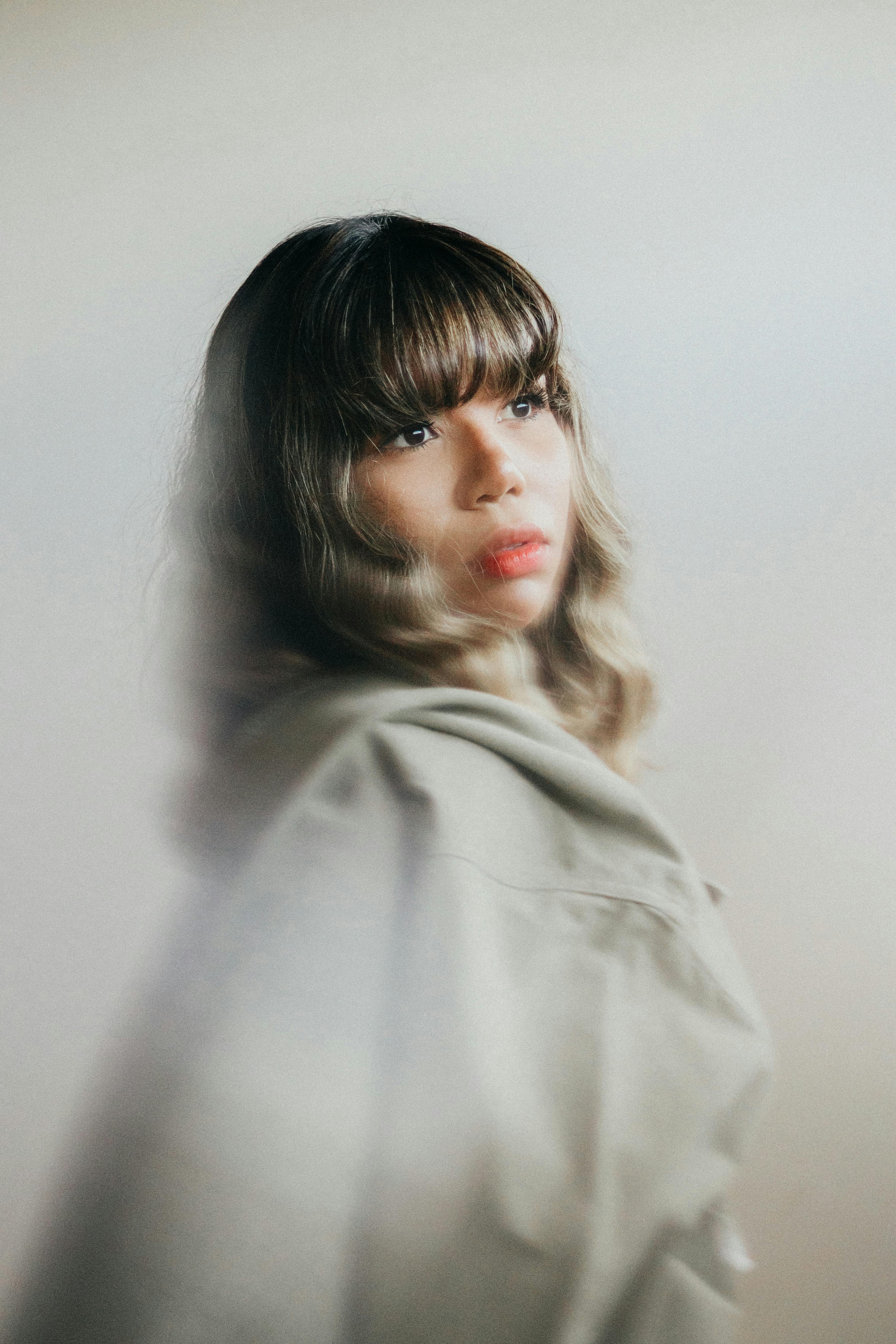 A dreamy portrait of a woman with bangs, captured in soft focus and neutral tones.