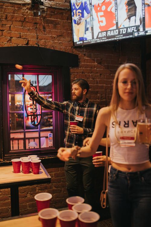 Free A lively evening scene with young adults playing beer pong at a Denver bar, enjoying a fun social gathering. Stock Photo
