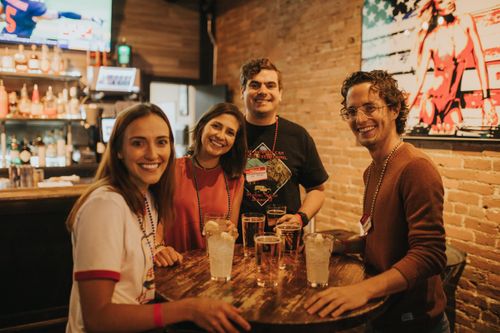 Free A group of friends smiling and enjoying drinks in a cozy Denver bar setting. Stock Photo