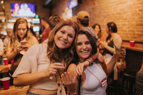 Free Women enjoying drinks and nightlife at a Denver bar, smiling and holding beverages. Stock Photo