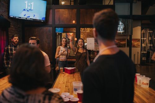 Free Group of friends enjoying a lively beer pong game at a Denver bar, capturing the spirit of fun and camaraderie. Stock Photo