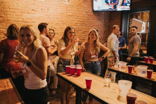 Free Energetic social gathering at a Denver pub featuring a lively beer pong game and cheerful participants. Stock Photo