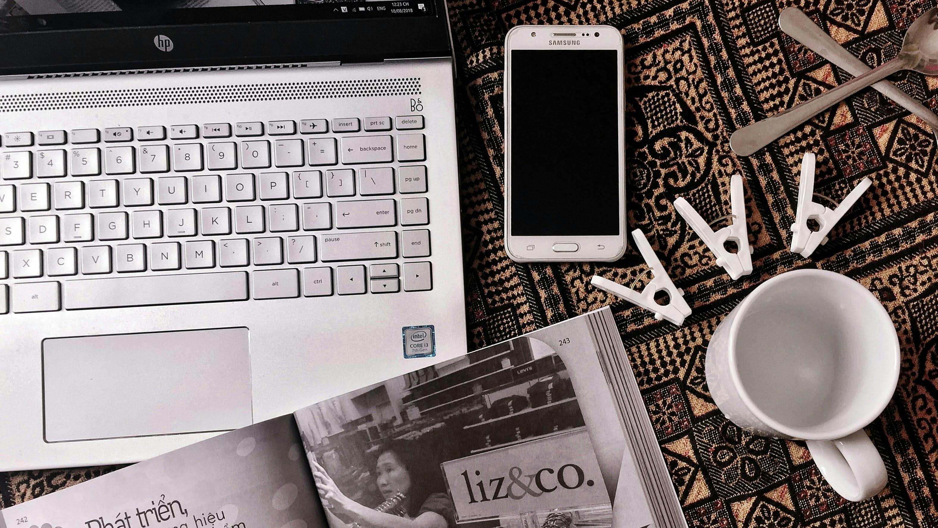 Artistic flat lay featuring a laptop, smartphone, and clothespins on a textured background.