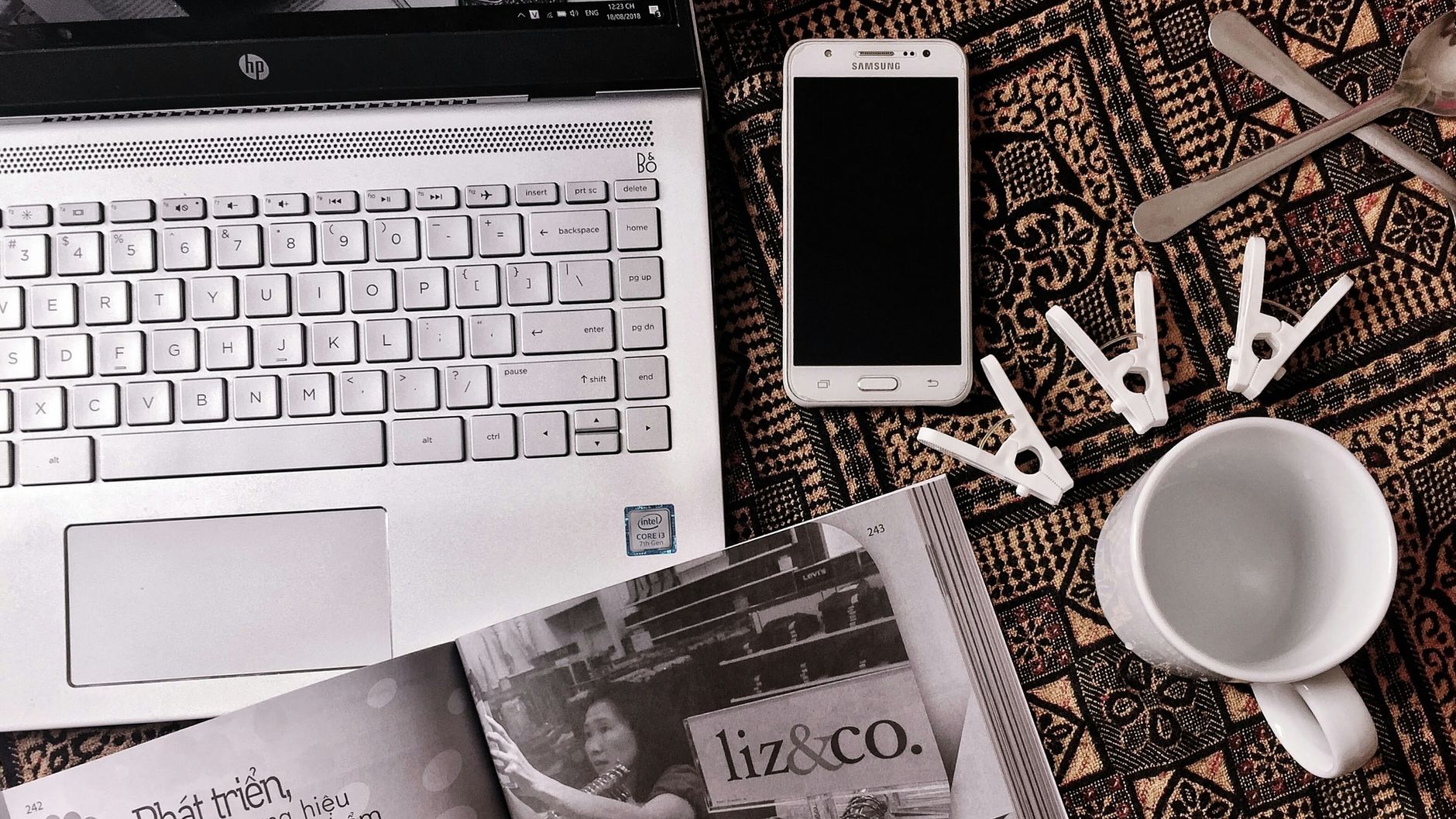 Artistic flat lay featuring a laptop, smartphone, and clothespins on a textured background.