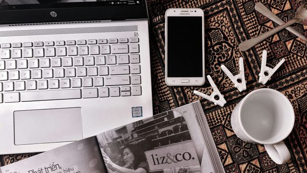 Artistic flat lay featuring a laptop, smartphone, and clothespins on a textured background.