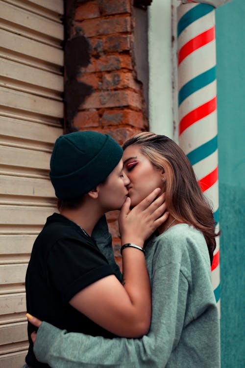 Photo of a Woman with a Beanie Kissing Another Woman