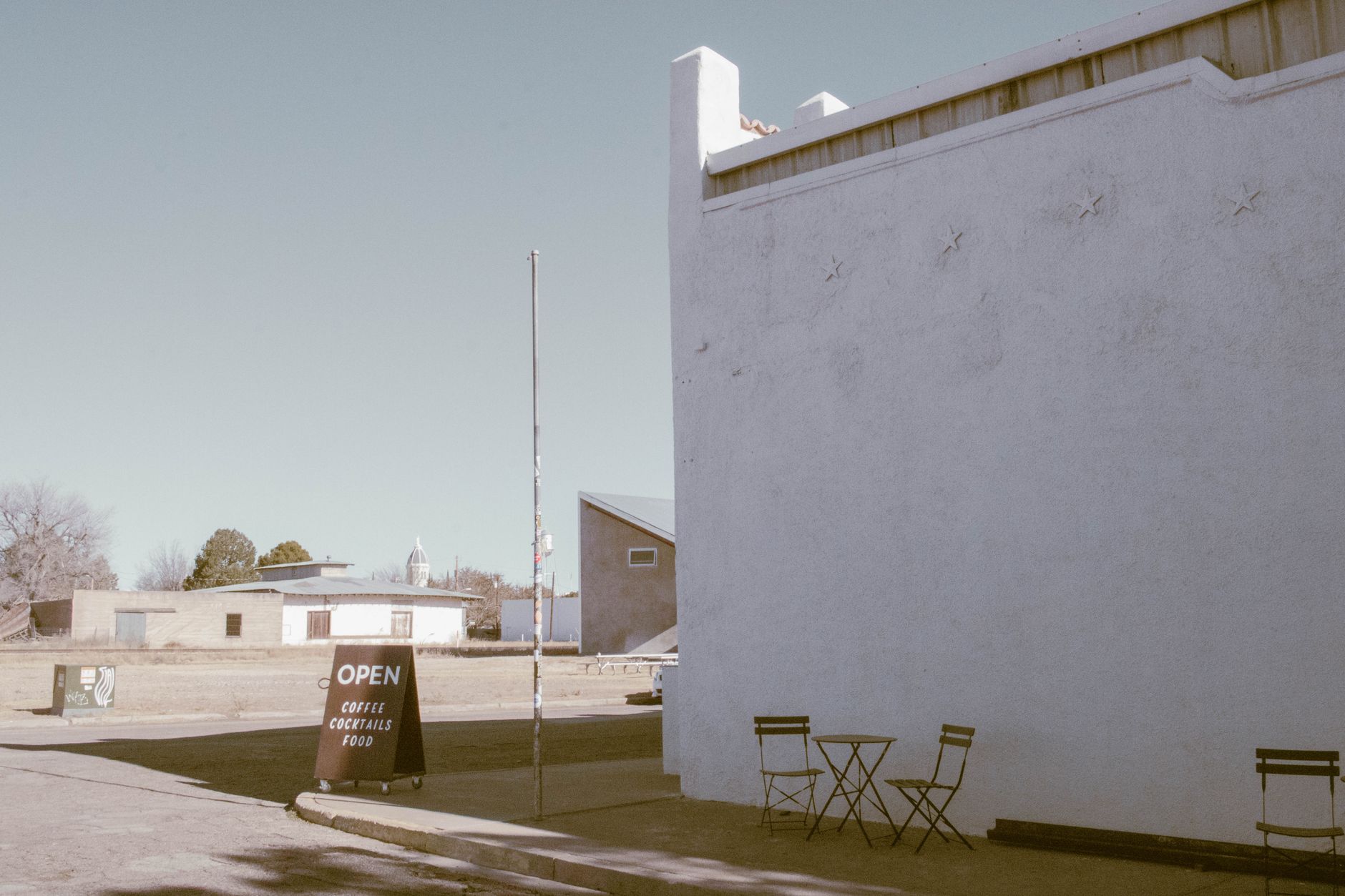 Stylish street view in Marfa, featuring a cafe sign and outdoor seating under a clear sky.