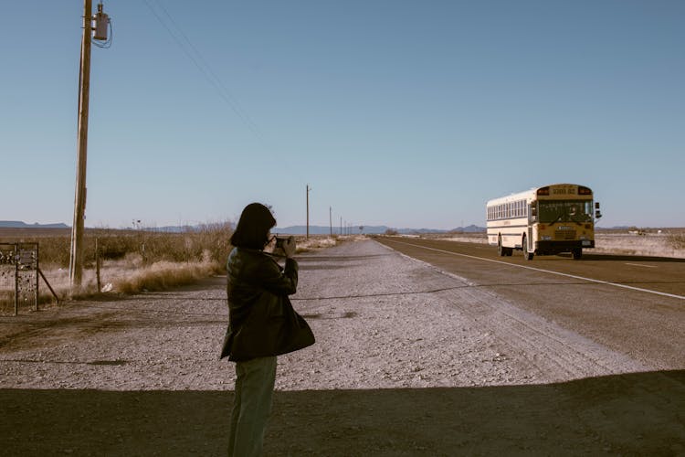 Photo Of A Woman Taking A Photo Of A School Bus