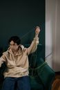 Man Sitting on the Green Sofa Holding a Green Thread