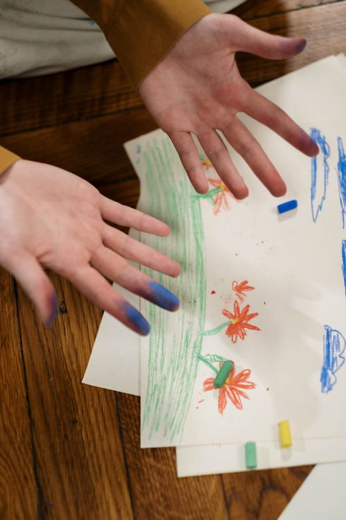 Free Hands with pastel stains from a child's drawing session, featuring colorful artwork on paper. Stock Photo
