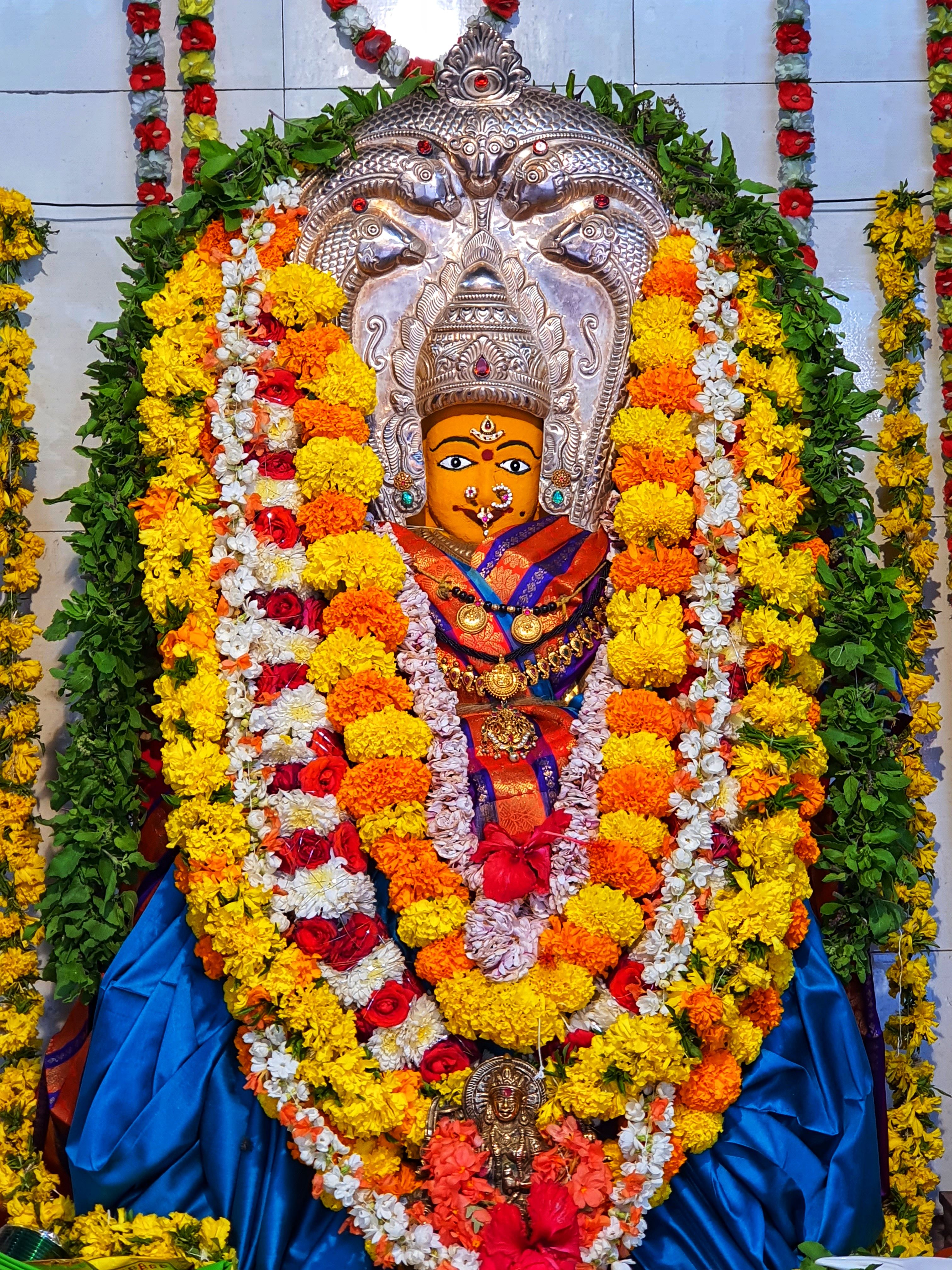 Colorful Hindu goddess idol adorned with vibrant flower garlands in an ornate setting.