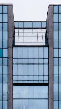 Modern building exterior with glass walls in daytime in city street under sky