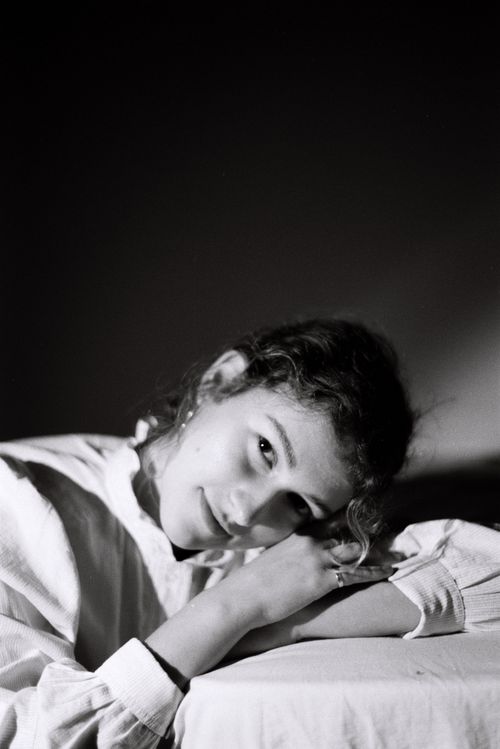 Free Captivating black and white portrait of a woman reclining and smiling, exuding elegance. Stock Photo