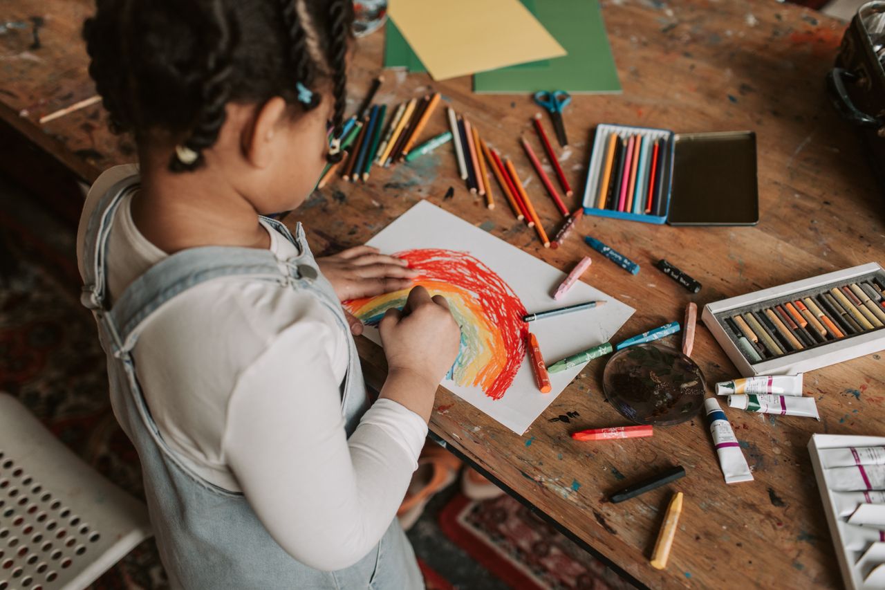 A child drawing with crayons for fun, emphasizing process over perfection.