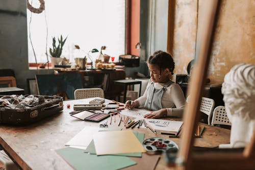 Photo of a Girl Drawing on a Paper