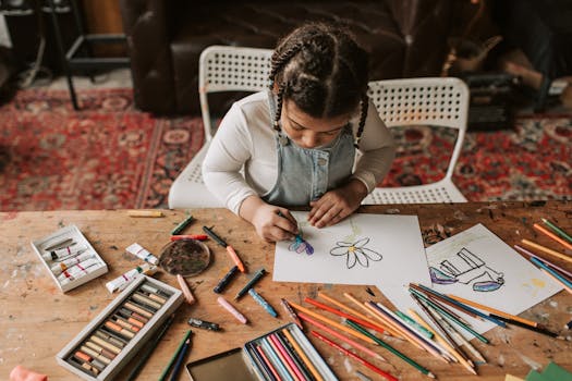 A young girl focused on drawing with crayons and colored pencils at a wooden table indoors.