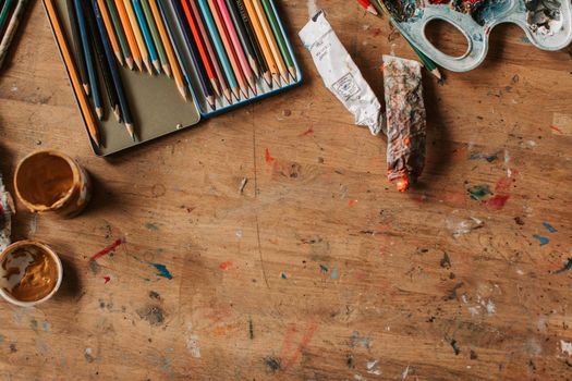 Top view of colorful art supplies on a wooden table, inspiring creativity.