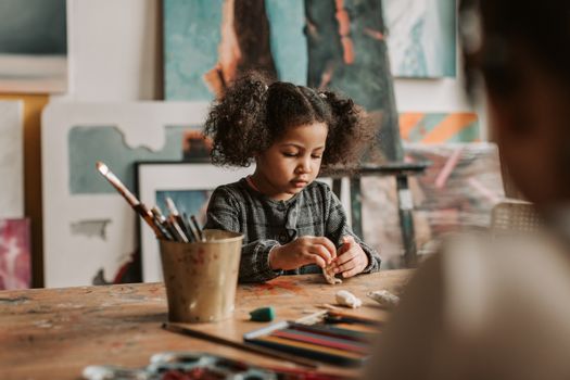 Little Girl Sculpting from Plasticine at the Wooden Table