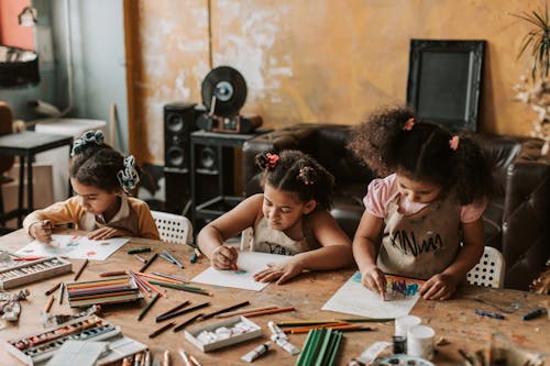 Three Girls Drawing at the Table