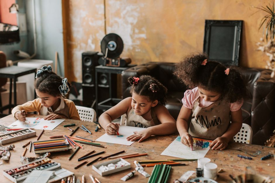 Home School Workshops 2 Three children focused on drawing at a table filled with coloring materials. | BocaVibe