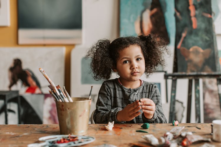 Little Girl Sculpting From Plasticine At The Table