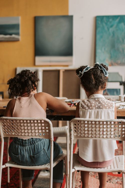 Free Two children sitting at a table in an art class focusing on creative activities. Stock Photo