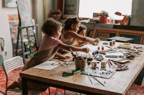 Free Three young girls engaged in painting at an indoor art studio, exploring their creativity. Stock Photo