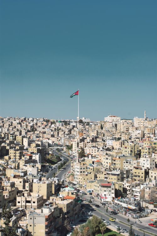 Free Aerial shot of Amman, Jordan showcasing cityscape and prominent national flag. Stock Photo
