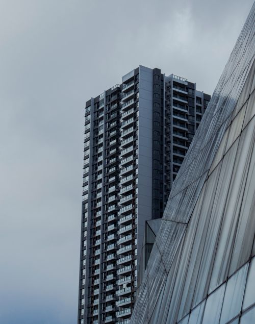 Free Tall skyscraper with a modern glass facade under a moody, cloudy sky. Stock Photo