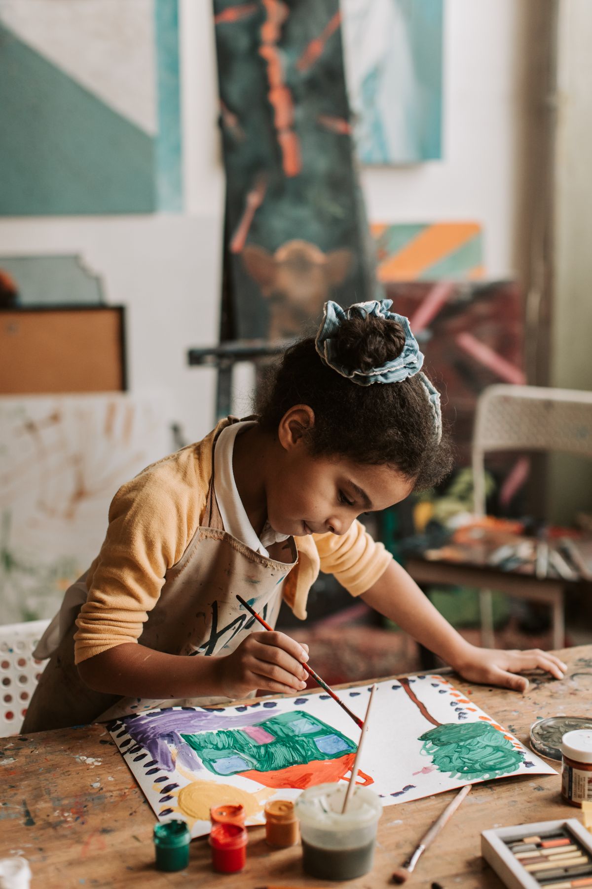 Young girl focusing intently on her painting project in an art classroom