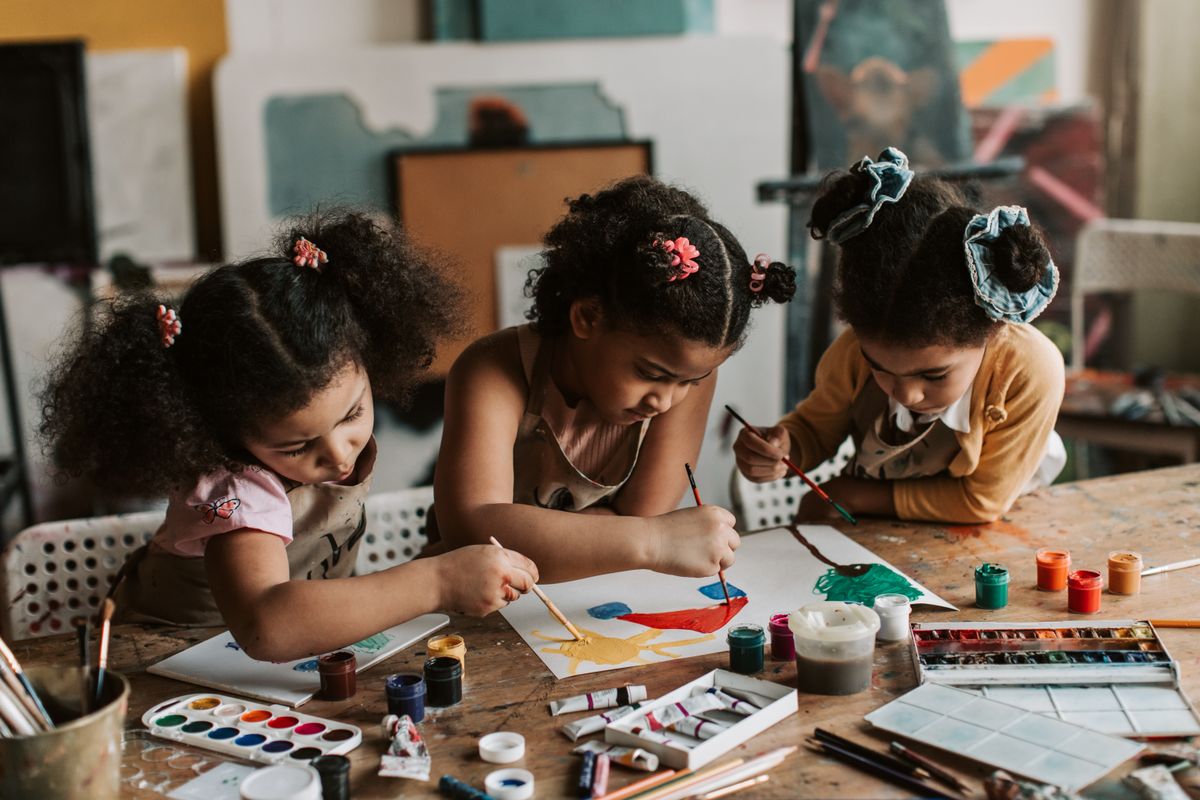 Three young girls painting together at an art table