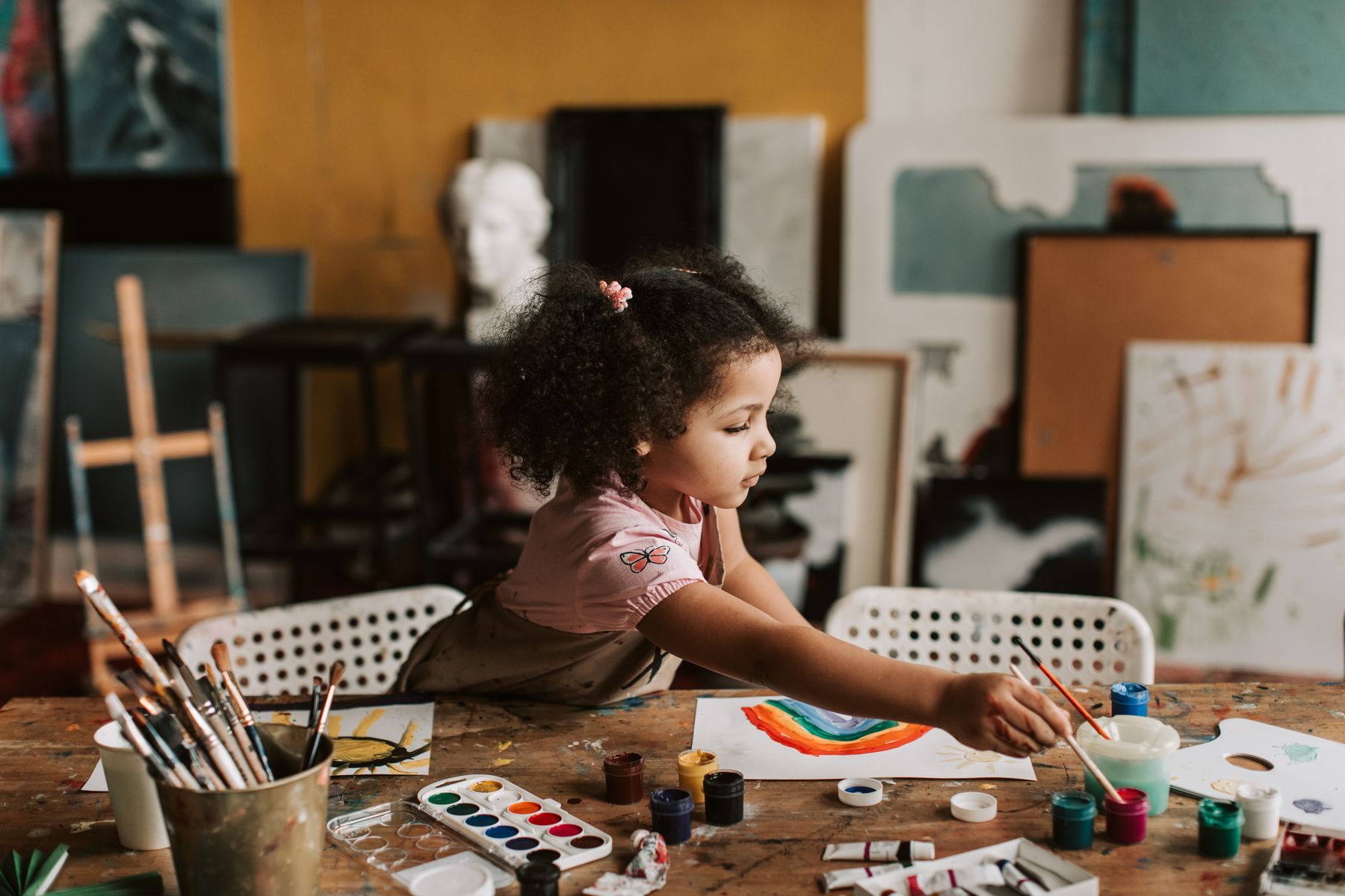 A young student painting a colourful artwork in an art studio