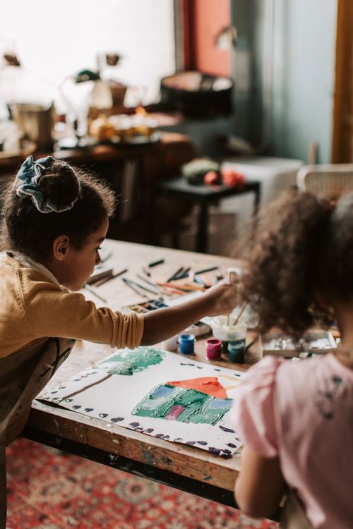 Free Two girls painting indoors using various art supplies, showcasing creativity and artistic expression. Stock Photo