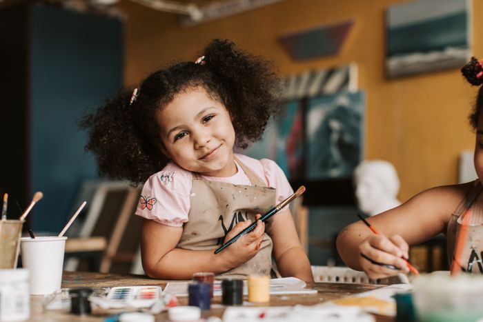 A child proudly showing a hand-painted Krishna artwork