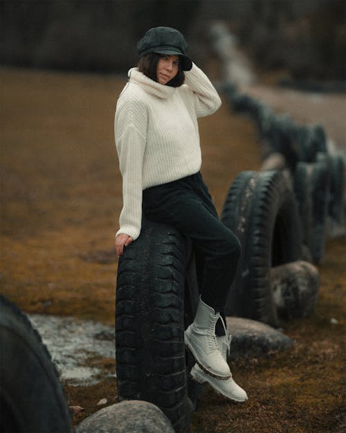 Woman in White Sweater Sitting on a Tire