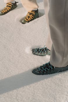 Two pairs of hiking boots with colorful laces on pristine winter snow. Perfect for adventure and travel themes.