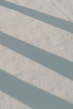 Abstract shadows cast on snow, capturing winter's serene beauty.