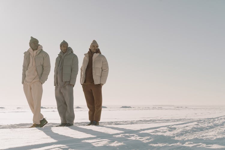 People In Winter Clothes Standing On Snow Covered Field