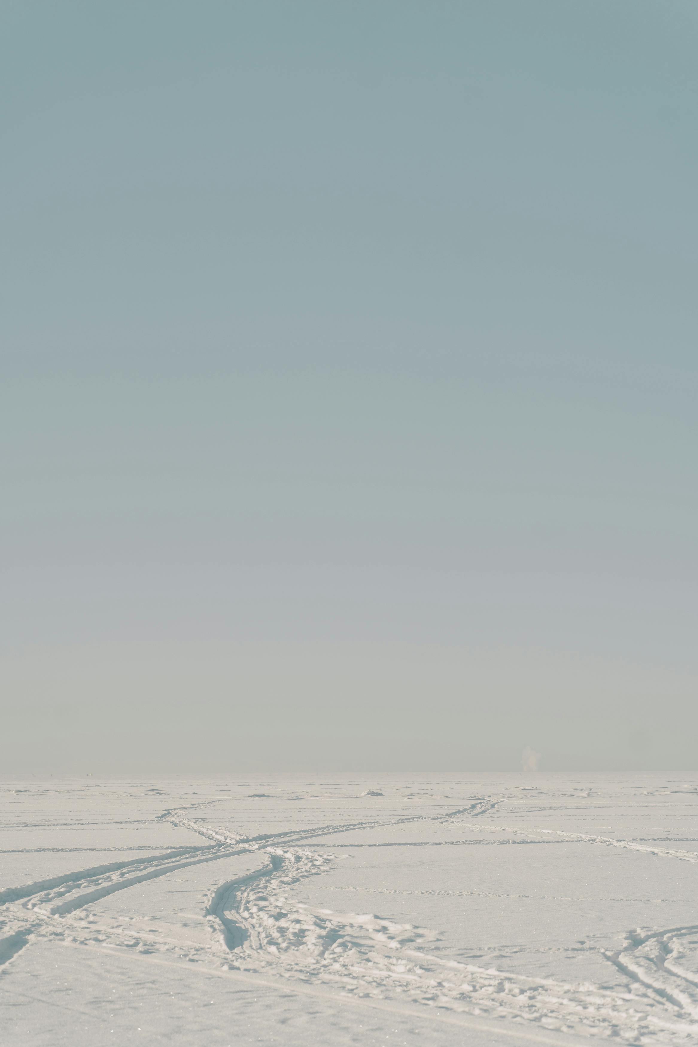 Serene snow-covered landscape with tracks under a clear blue sky.