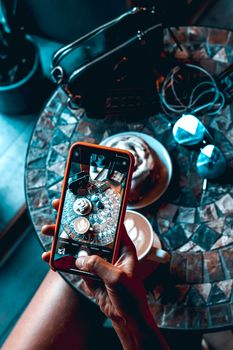 A modern coffee table scene featuring a cinnamon roll and coffee captured on a smartphone.