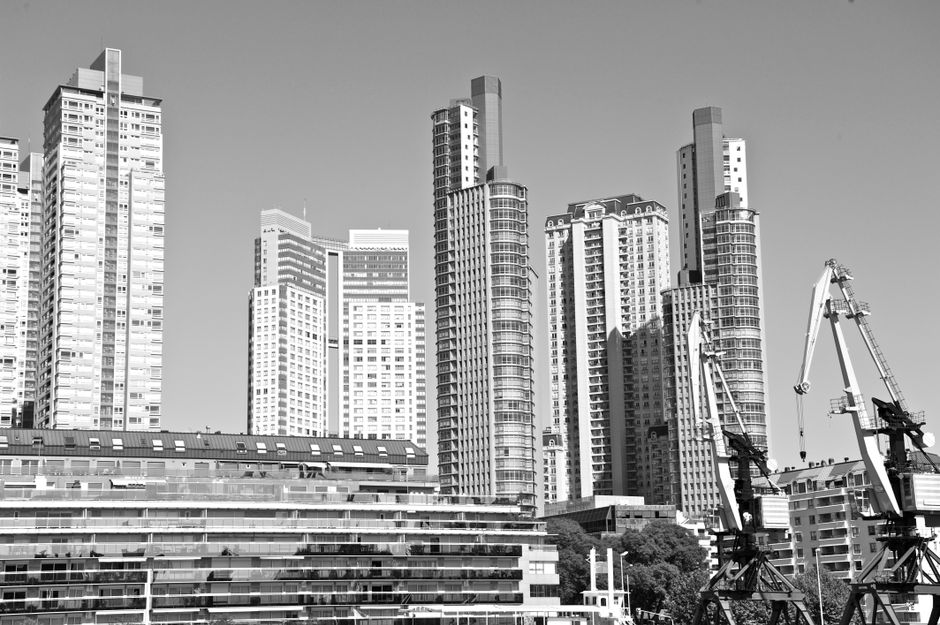 Imagen en monocromo que muestra una fila de rascacielos con grúas de construcción en primer plano.