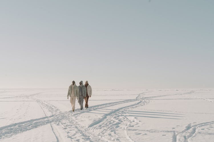 Photograph Of Men In Puffer Jackets Walking On The Snow