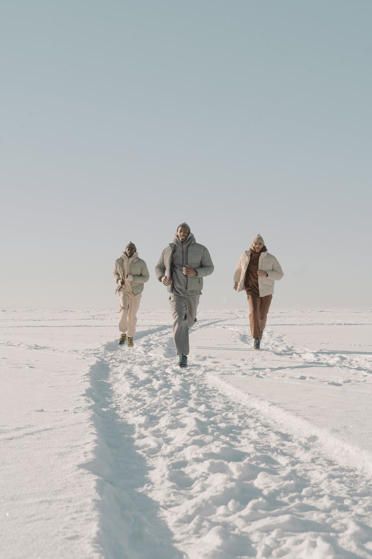 Men Running Together On Snow Covered Land