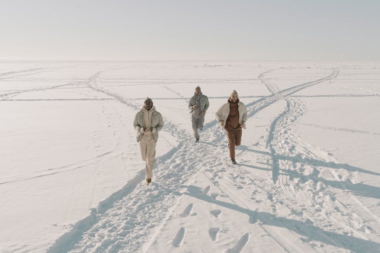 Group Of Men Running On Snow Covered Land