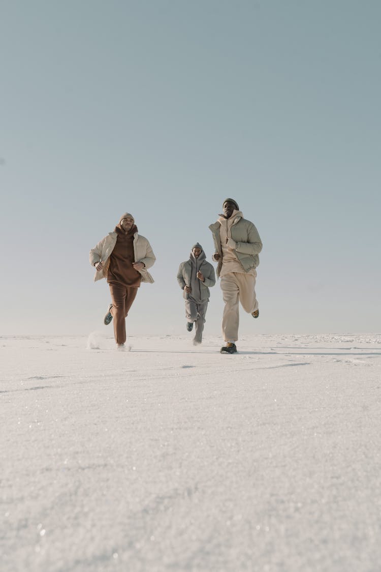 Men In Winter Clothes Running On Snow