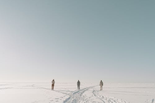 People Standing on Snow with Footprints