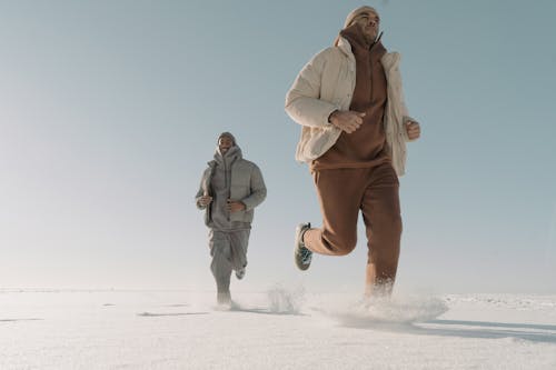 Free Man Wearing Puffer Jackets Running on Thick Snow Stock Photo