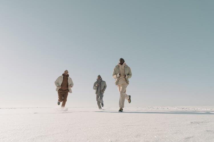 Group Of People Running On Snow Covered Land